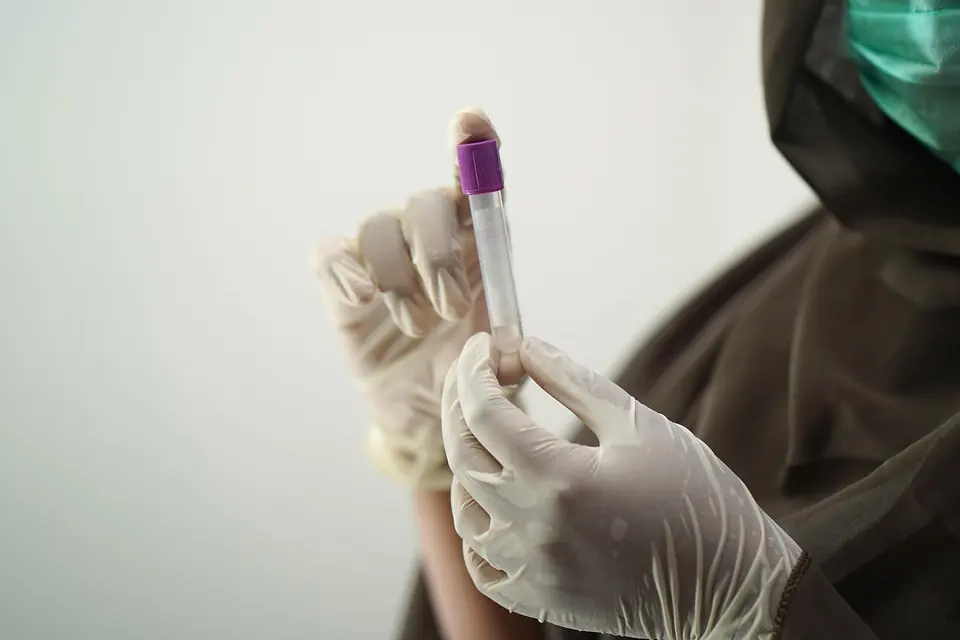 A gloved hand holding a blood sample tube