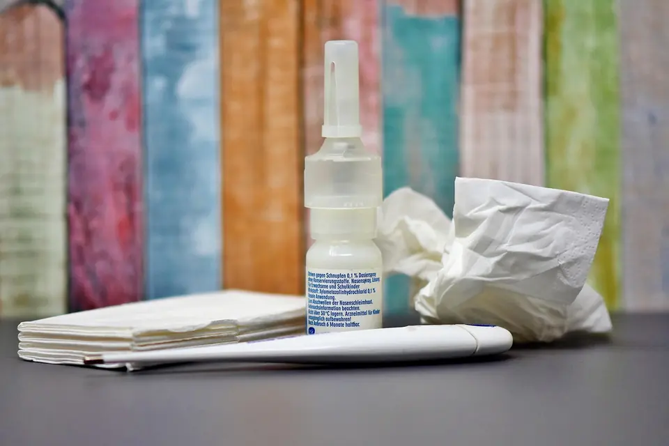 Tissues, nasal spray and a notebook on a desk