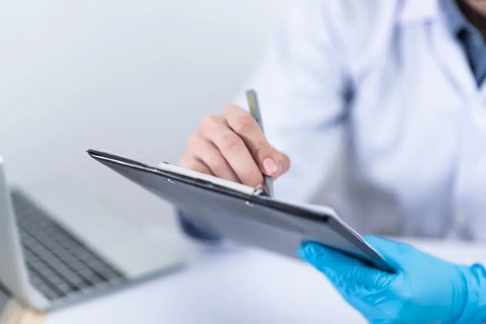 A doctor writing notes on a clipboard during a consultation