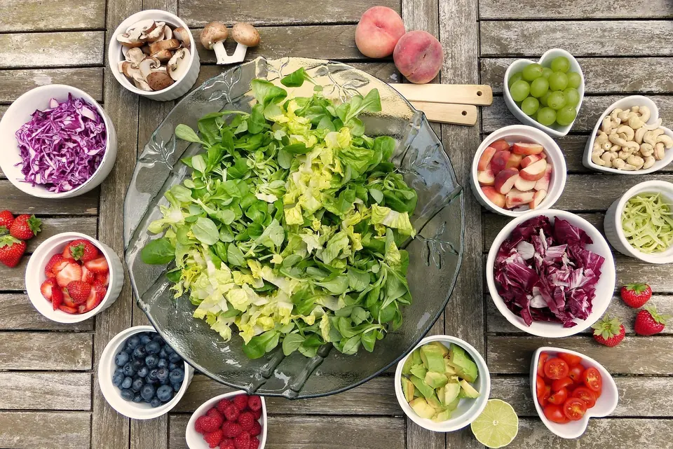 A table of salad, fruit and vegetables in small bowls