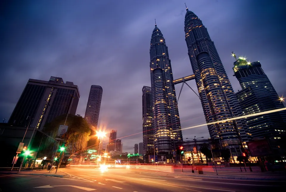 Kuala Lumpur’s Petronas Twin Towers under a dark, cloudy evening sky