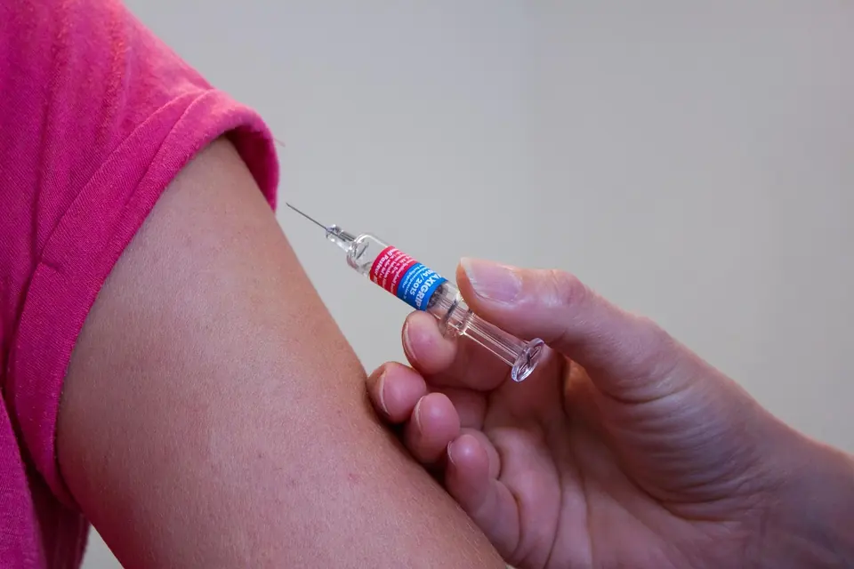 A doctor giving a vaccine injection in the upper arm