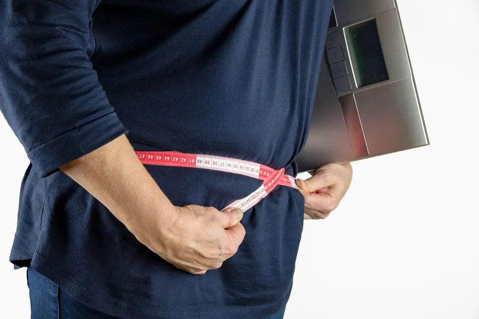 A man measuring his waist with a tape measure